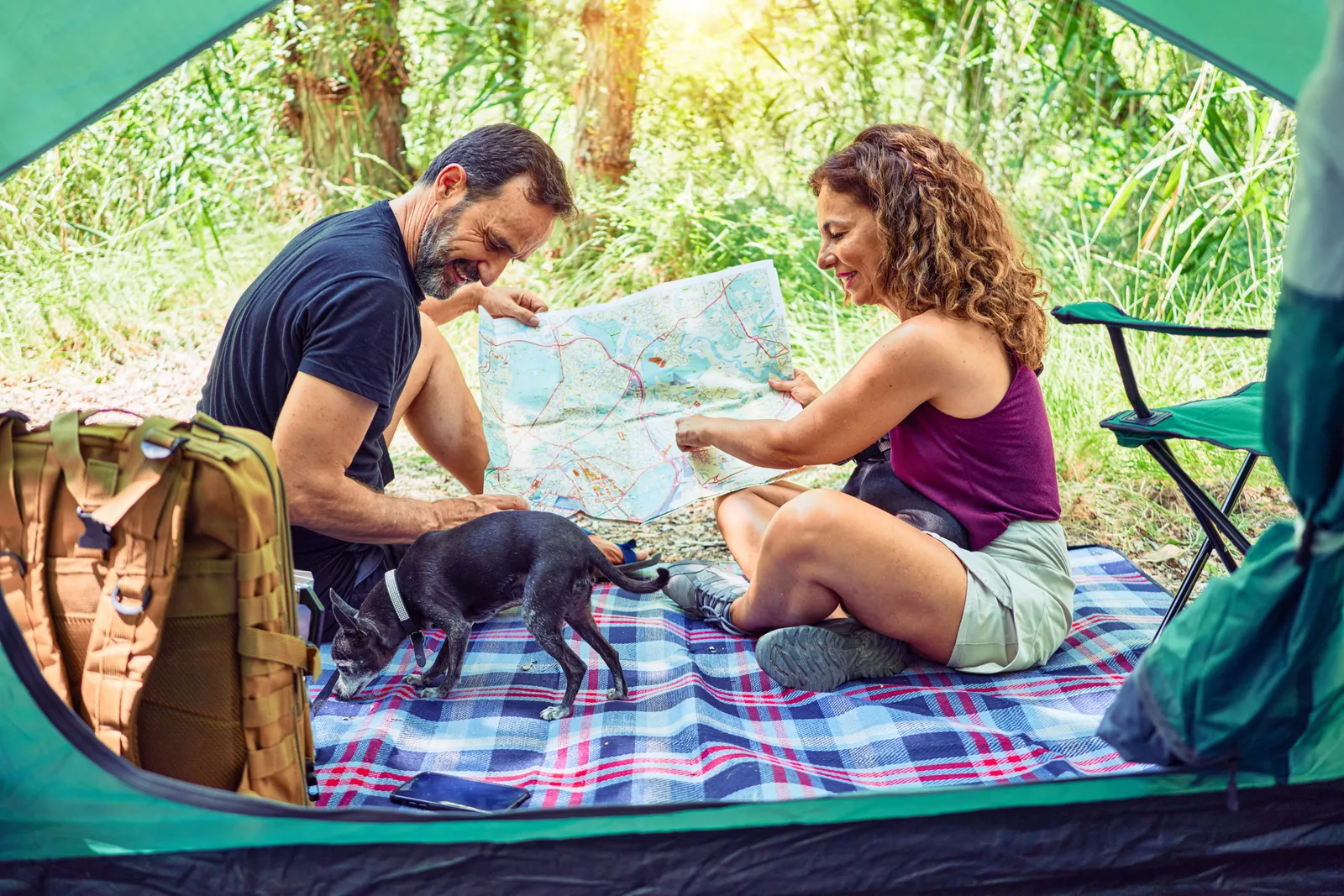 A couple inside a small tent reading a paper map together, the kind of low-key planning that builds the post-retreat habit.