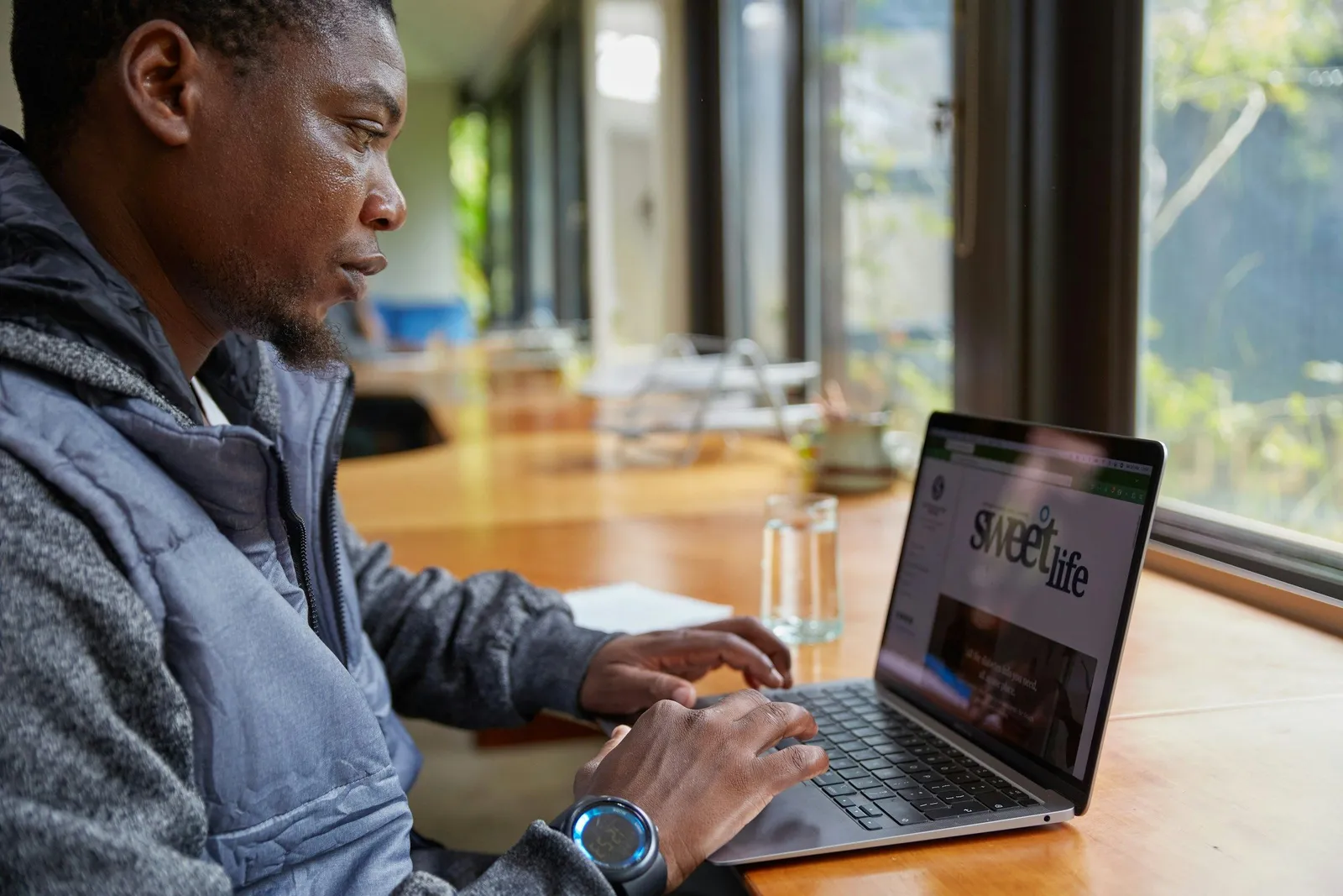 Man working at a laptop near a sunlit window, quiet focused workspace in natural light